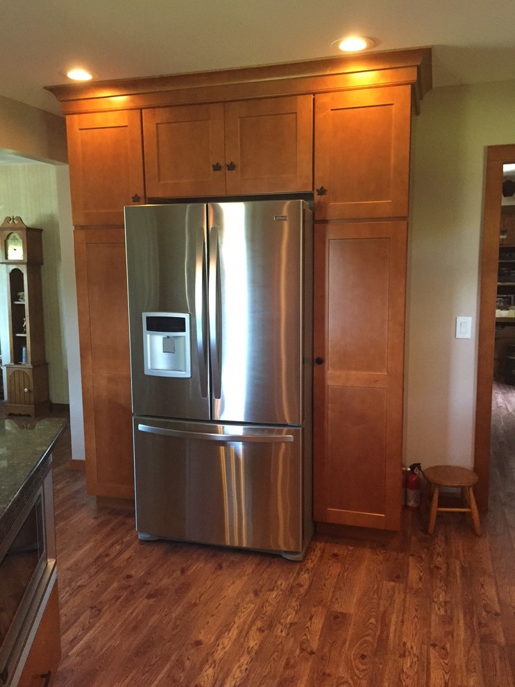 Mid-sized transitional l-shaped medium tone wood floor eat-in kitchen photo in Boston with an undermount sink, shaker cabinets, medium tone wood cabinets, granite countertops, beige backsplash, stainless steel appliances and an island