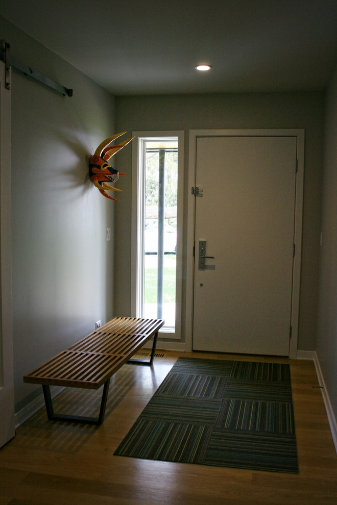 Photo of a mid-sized midcentury mudroom in Chicago with grey walls, medium hardwood floors, a single front door and a white front door.