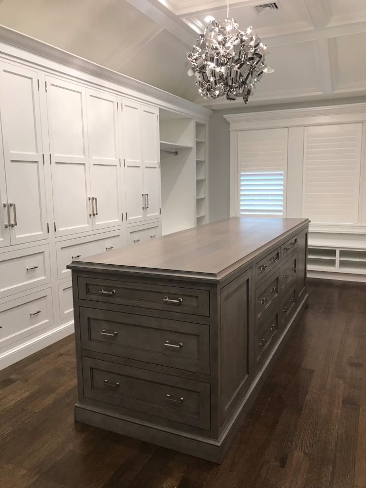 Large traditional walk-in wardrobe in New York with recessed-panel cabinets, dark wood cabinets, dark hardwood flooring, brown floors and a drop ceiling.