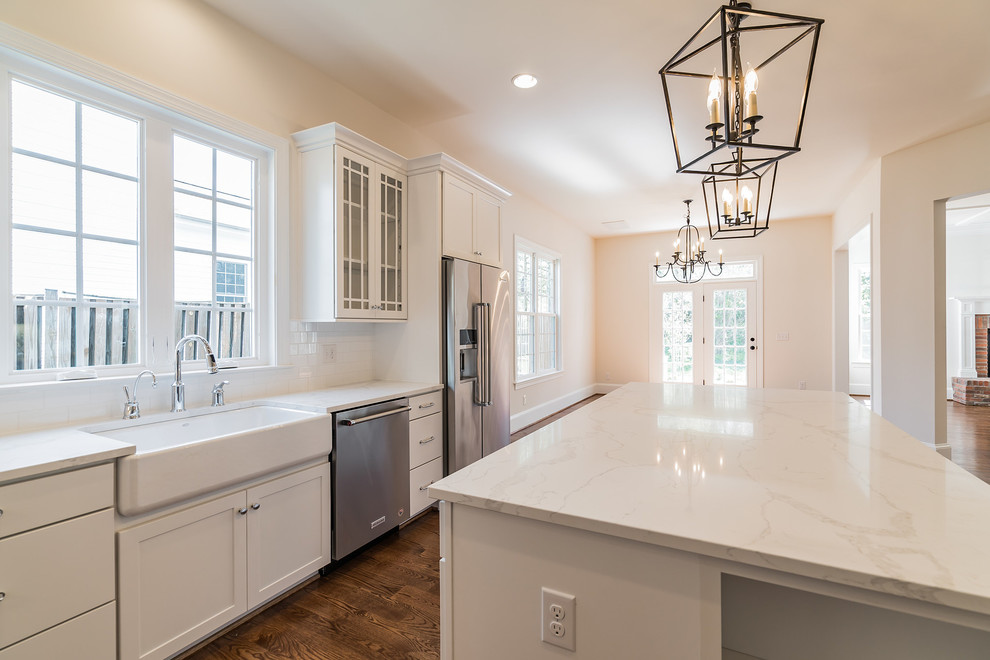 Inspiration for a large traditional u-shaped eat-in kitchen in DC Metro with a farmhouse sink, shaker cabinets, white cabinets, quartz benchtops, white splashback, subway tile splashback, stainless steel appliances, medium hardwood floors, with island and white benchtop.
