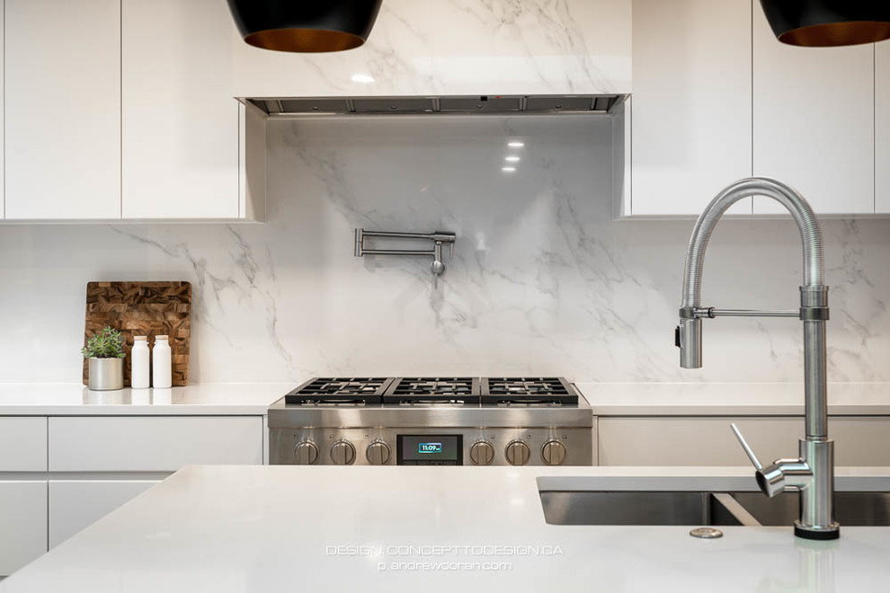 Photo of a mid-sized modern l-shaped open plan kitchen in Vancouver with an undermount sink, flat-panel cabinets, white cabinets, quartzite benchtops, white splashback, porcelain splashback, stainless steel appliances, medium hardwood floors, with island and white benchtop.