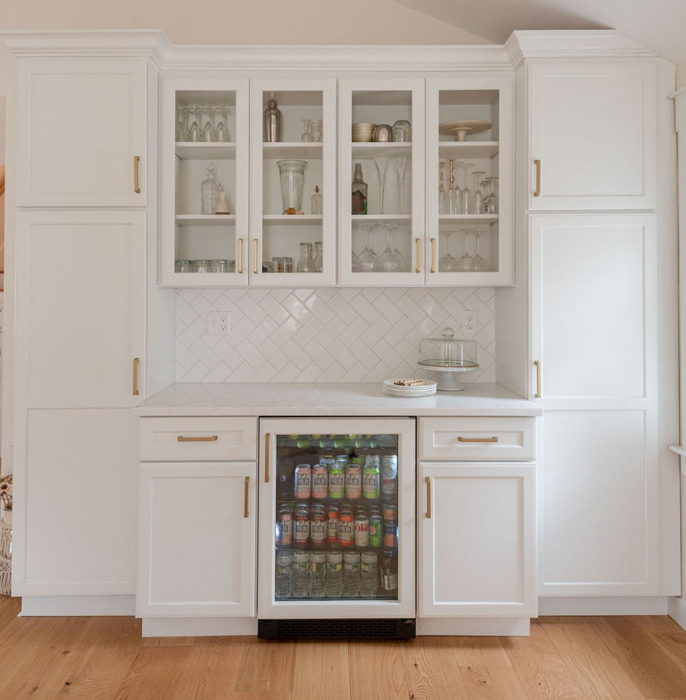 Inspiration for a huge transitional l-shaped light wood floor, brown floor and vaulted ceiling eat-in kitchen remodel in Boston with an undermount sink, shaker cabinets, white cabinets, quartz countertops, white backsplash, ceramic backsplash, paneled appliances, an island and white countertops