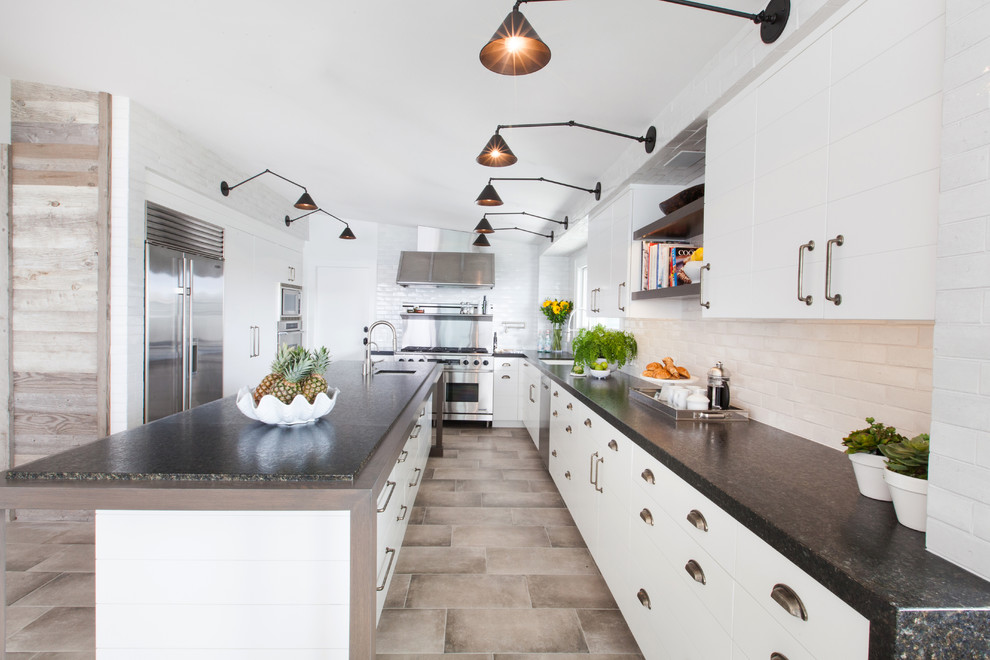 Design ideas for a mid-sized contemporary u-shaped open plan kitchen in Orange County with stainless steel appliances, an undermount sink, louvered cabinets, white cabinets, granite benchtops, white splashback, brick splashback, porcelain floors, with island and beige floor.