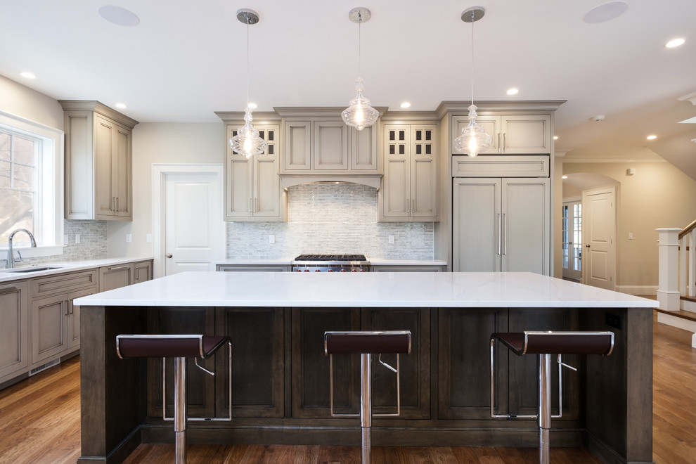 Photo of a large traditional u-shaped kitchen in Boston with an undermount sink, beaded inset cabinets, grey cabinets, quartz benchtops, ceramic splashback, panelled appliances, dark hardwood floors, with island, brown floor and beige splashback.