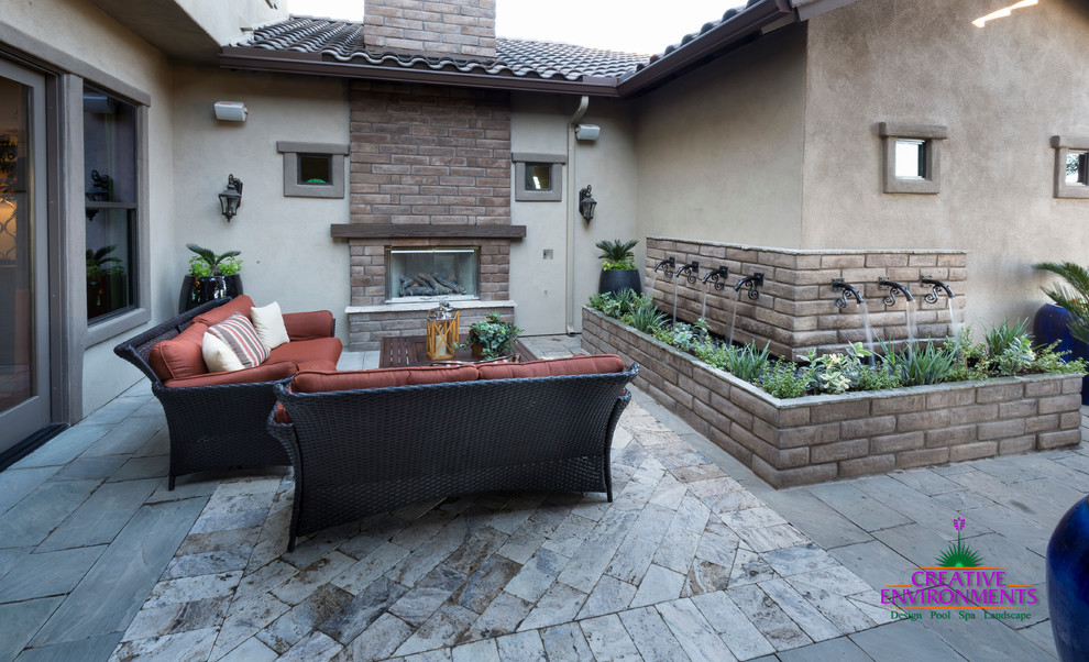 Photo of an expansive modern front yard patio in Phoenix with a fire feature, brick pavers and a pergola.