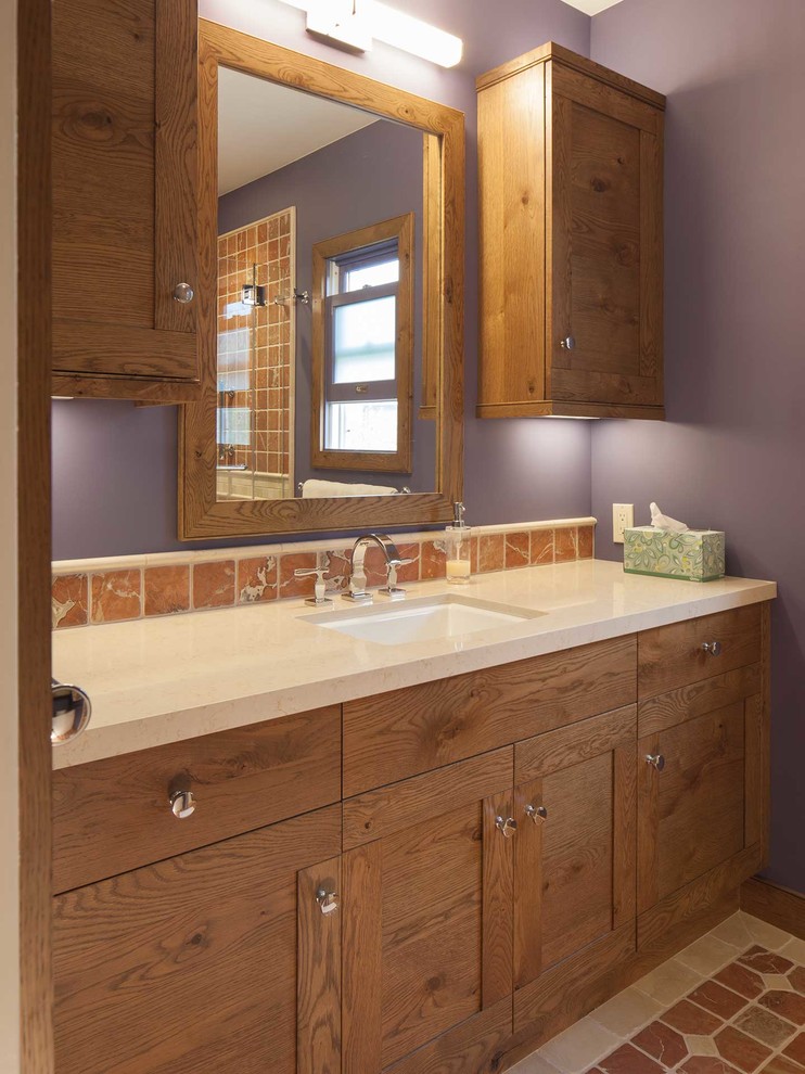 This is an example of a mid-sized eclectic master bathroom in San Francisco with an undermount sink, shaker cabinets, medium wood cabinets, engineered quartz benchtops, a curbless shower, orange tile, stone tile, purple walls and travertine floors.