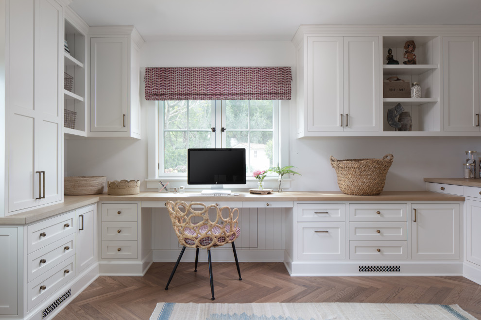 Immagine di un ampio ufficio country con pareti bianche, pavimento in legno massello medio, scrivania incassata, pavimento marrone e travi a vista