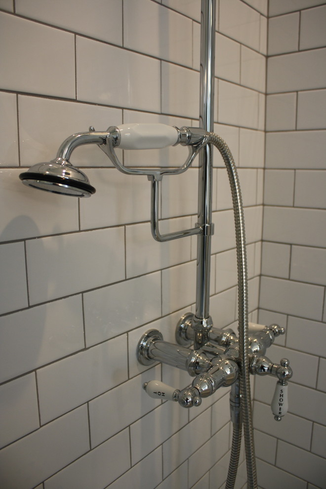 This is an example of a mid-sized traditional 3/4 bathroom in Houston with furniture-like cabinets, black cabinets, a claw-foot tub, a corner shower, a two-piece toilet, white tile, subway tile, grey walls, ceramic floors, an undermount sink, solid surface benchtops, multi-coloured floor and a hinged shower door.