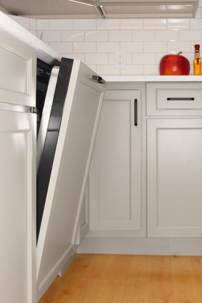 Inspiration for a large transitional u-shaped light wood floor and brown floor enclosed kitchen remodel in Boston with a double-bowl sink, shaker cabinets, gray cabinets, quartz countertops, white backsplash, porcelain backsplash, black appliances, an island and white countertops