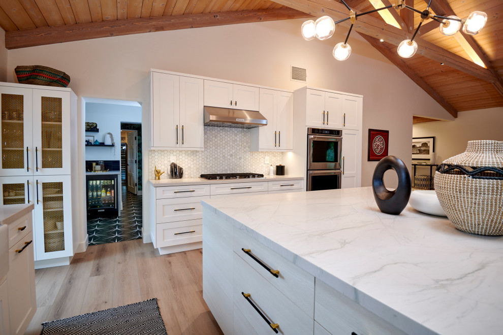 Idéer för att renovera ett stort vintage vit vitt kök, med en undermonterad diskho, luckor med infälld panel, vita skåp, bänkskiva i kvartsit, vitt stänkskydd, stänkskydd i marmor, rostfria vitvaror, mellanmörkt trägolv, en köksö och brunt golv