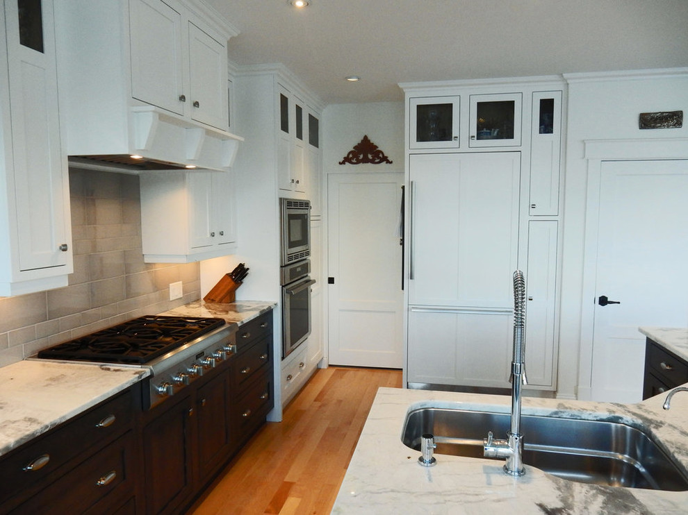 Open concept kitchen - mid-sized transitional l-shaped medium tone wood floor and brown floor open concept kitchen idea with an undermount sink, beaded inset cabinets, white cabinets, quartz countertops, gray backsplash, ceramic backsplash, stainless steel appliances, an island and white countertops