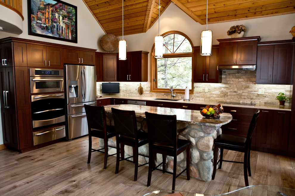 Eat-in kitchen - large rustic l-shaped light wood floor and beige floor eat-in kitchen idea in Toronto with an undermount sink, shaker cabinets, dark wood cabinets, granite countertops, beige backsplash, stone tile backsplash, stainless steel appliances and an island
