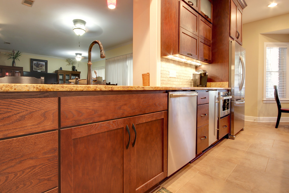 Eat-in kitchen - transitional eat-in kitchen idea in Miami with an undermount sink, shaker cabinets, brown cabinets, granite countertops, beige backsplash, stone tile backsplash and stainless steel appliances