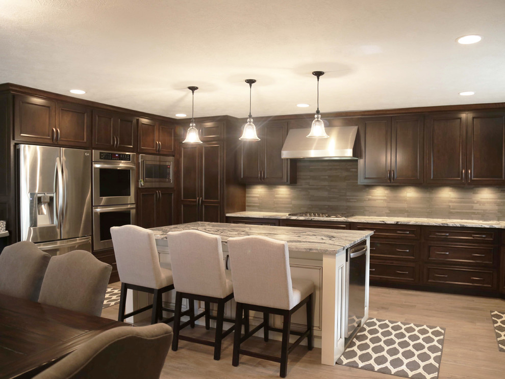 Inspiration for a mid-sized transitional l-shaped porcelain tile eat-in kitchen remodel with an undermount sink, raised-panel cabinets, dark wood cabinets, granite countertops, gray backsplash, porcelain backsplash, stainless steel appliances and an island
