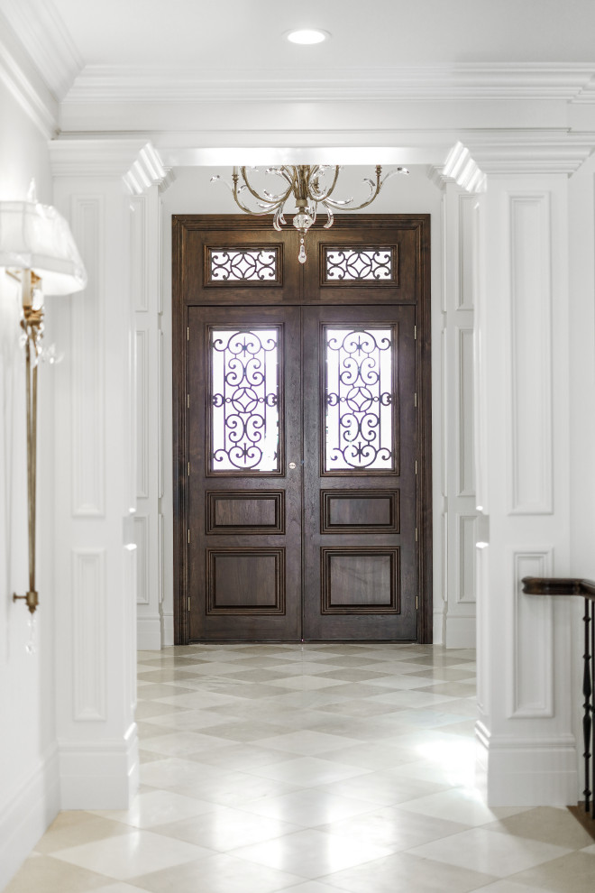 Exemple d'un grand hall d'entrée avec un mur blanc, un sol en marbre, une porte double, une porte en bois foncé, un sol blanc et un plafond voûté.