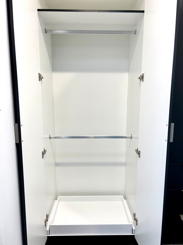 Cette image montre une petite armoire encastrée traditionnelle neutre avec un placard à porte plane et des portes de placard noires.