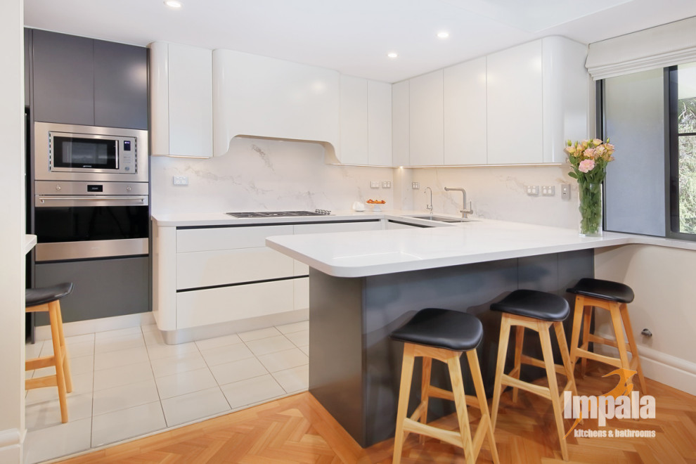 Inspiration for a mid-sized modern u-shaped separate kitchen in Sydney with a double-bowl sink, flat-panel cabinets, white cabinets, quartz benchtops, white splashback, stone slab splashback, stainless steel appliances, ceramic floors, with island, beige floor and white benchtop.