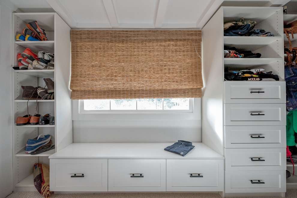 This is an example of a mid-sized transitional gender-neutral walk-in wardrobe in Los Angeles with shaker cabinets, white cabinets, carpet and beige floor.