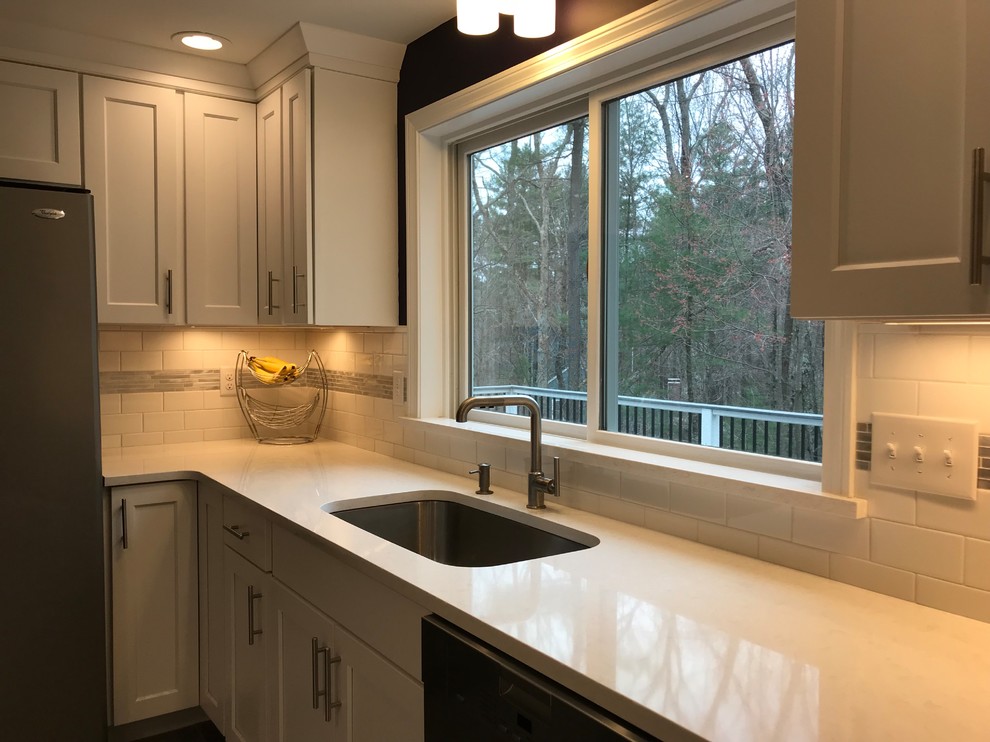 Inspiration for a mid-sized transitional galley eat-in kitchen in Boston with an undermount sink, shaker cabinets, white cabinets, quartz benchtops, white splashback, porcelain splashback, stainless steel appliances, porcelain floors, with island and grey floor.