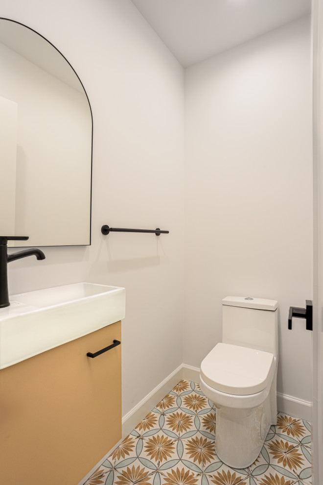 Kleine Klassische Gästetoilette mit flächenbündigen Schrankfronten, orangefarbenen Schränken, Toilette mit Aufsatzspülkasten, weißer Wandfarbe, Zementfliesen für Boden, integriertem Waschbecken, Mineralwerkstoff-Waschtisch, buntem Boden, weißer Waschtischplatte und schwebendem Waschtisch in Los Angeles