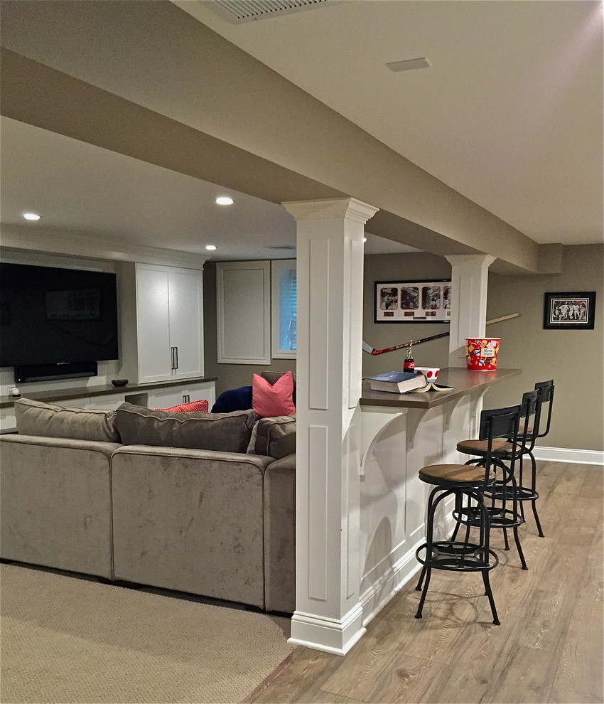 Large transitional underground laminate floor and gray floor basement photo in Other with beige walls
