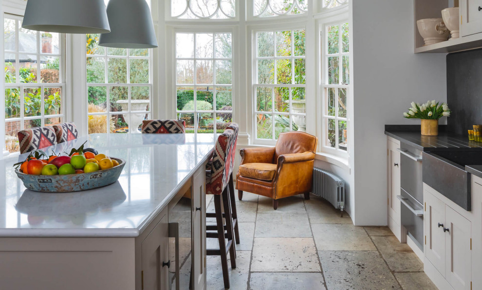 Example of a large classic galley open concept kitchen design in London with shaker cabinets, quartzite countertops, an island and gray countertops