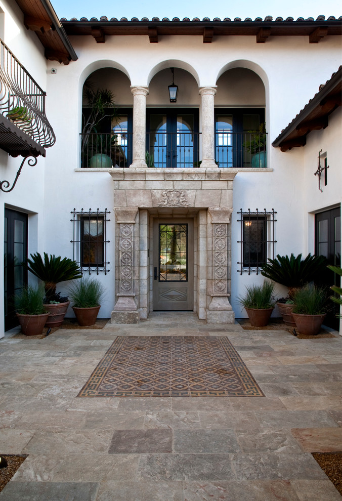 This is an example of a mediterranean front door in Orange County with white walls and a single front door.