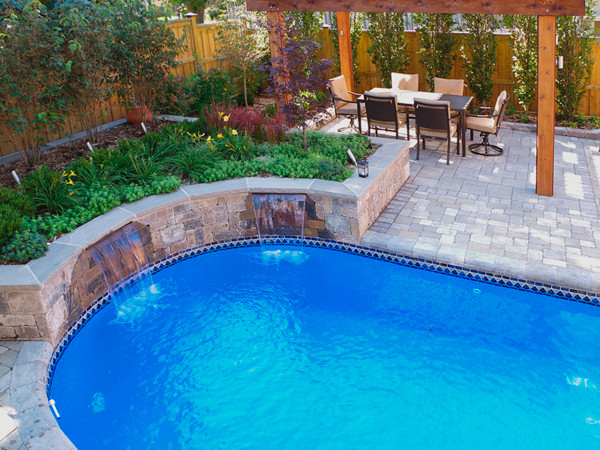 Design ideas for a mid-sized contemporary backyard pool in Toronto with natural stone pavers.