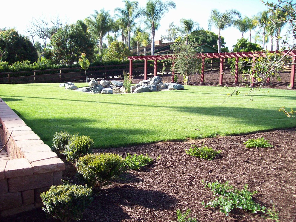 This is an example of a large traditional backyard partial sun garden for spring in San Diego with with pond and mulch.