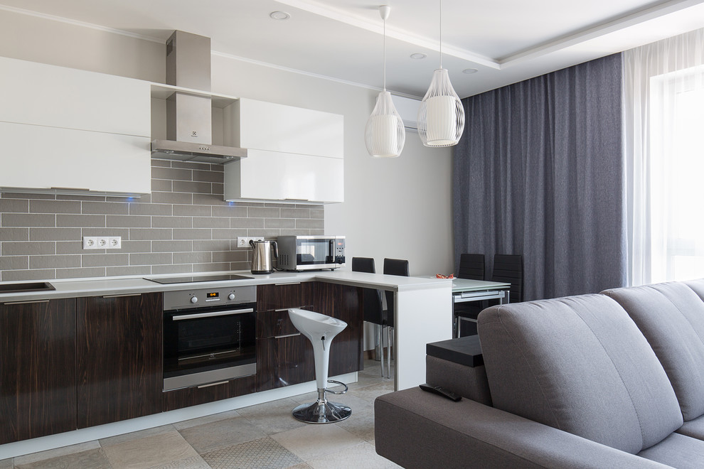 Photo of a contemporary l-shaped open plan kitchen in Other with flat-panel cabinets, dark wood cabinets, grey splashback, stainless steel appliances, no island, grey floor and white benchtop.