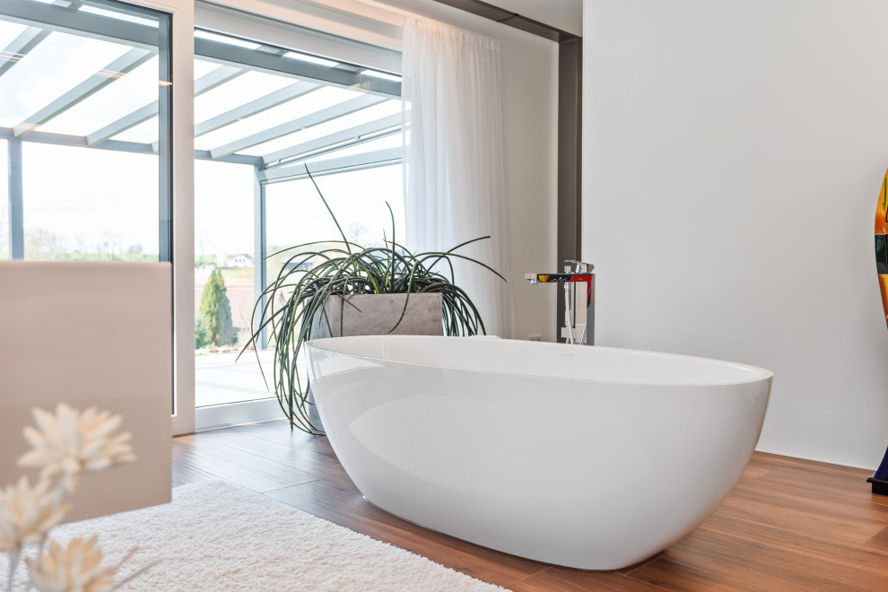 Badezimmer En Suite With flächenbündigen Schrankfronten, weißen Schränken, freistehender Badewanne, Wandtoilette, braunen Fliesen, Fliesen in Holzoptik, weißer Wandfarbe, Keramikboden, Wandwaschbecken, grauem Boden, weißer Waschtischplatte, WC-Raum, Einzelwaschbecken, schwebendem Waschtisch and eingelassener Decke in Nuremberg