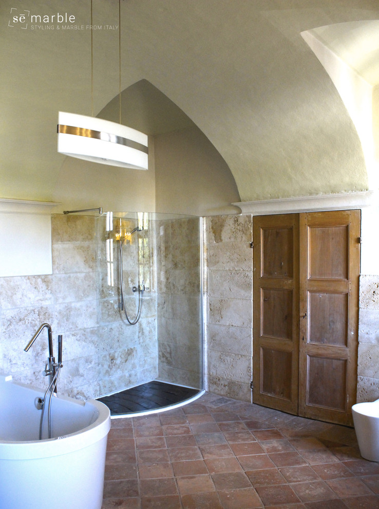 This is an example of a large contemporary master bathroom in Turin with flat-panel cabinets, light wood cabinets, an alcove tub, a corner shower, a two-piece toilet, marble, white walls, terra-cotta floors, a trough sink, marble benchtops, red floor and a hinged shower door.