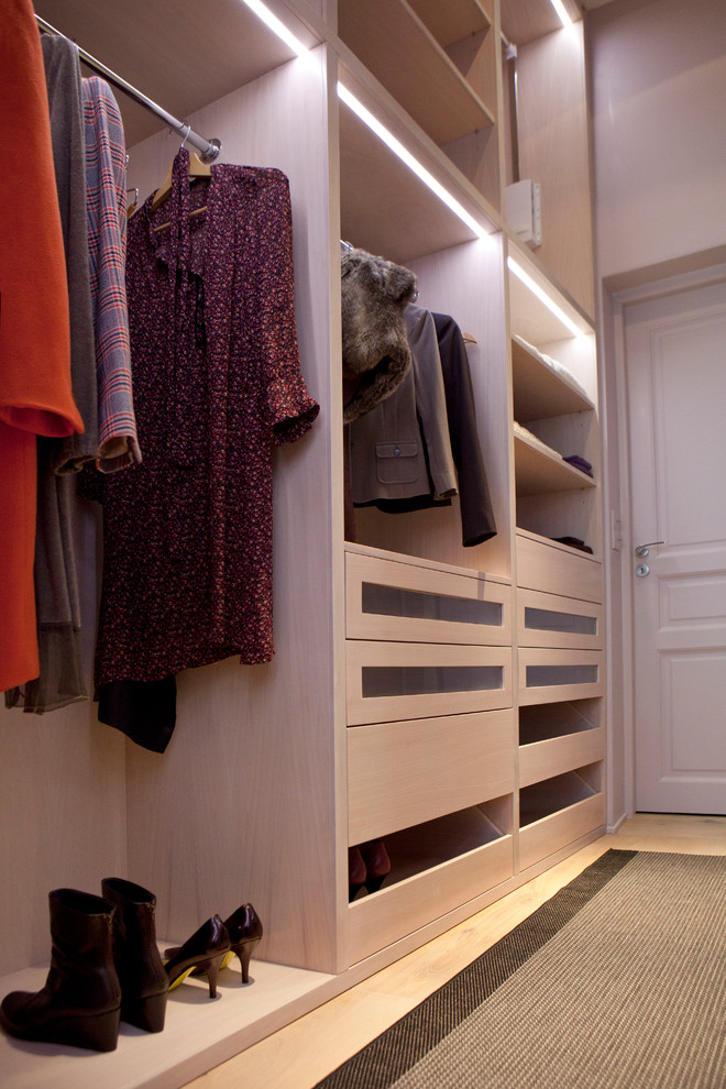 Design ideas for a small contemporary women's dressing room in Paris with open cabinets, light wood cabinets, light hardwood floors and brown floor.