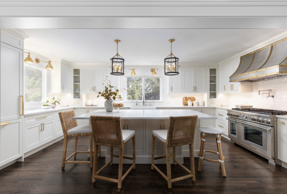 Example of a mid-sized transitional u-shaped dark wood floor and brown floor enclosed kitchen design in Detroit with a farmhouse sink, beaded inset cabinets, white cabinets, quartz countertops, white backsplash, subway tile backsplash, stainless steel appliances, an island and white countertops