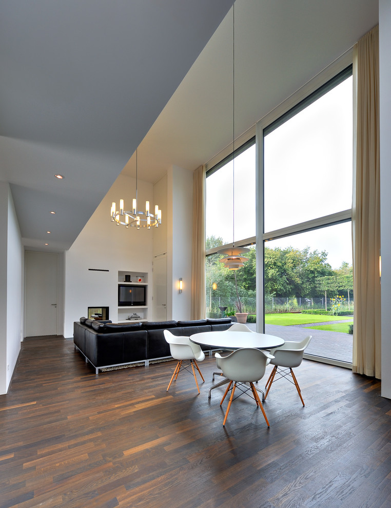 Large contemporary open plan dining in Berlin with white walls and dark hardwood floors.