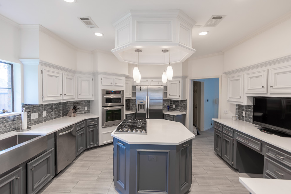 Example of a mid-sized transitional u-shaped ceramic tile and gray floor enclosed kitchen design in Austin with a farmhouse sink, recessed-panel cabinets, white cabinets, quartzite countertops, blue backsplash, glass tile backsplash, stainless steel appliances, an island and white countertops