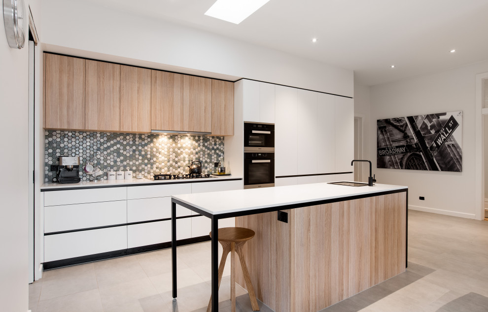 Photo of a contemporary galley open plan kitchen with a drop-in sink, flat-panel cabinets, white cabinets, quartz benchtops, multi-coloured splashback, panelled appliances, with island, beige floor and white benchtop.