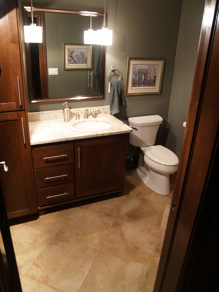 Mid-sized transitional 3/4 beige tile and porcelain tile porcelain tile bathroom photo in Milwaukee with recessed-panel cabinets, dark wood cabinets, a two-piece toilet, green walls, an undermount sink and granite countertops
