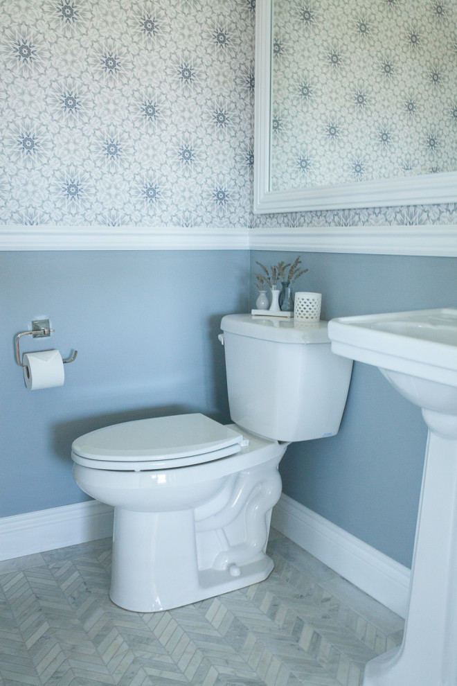 Design ideas for a small transitional bathroom in Boise with a two-piece toilet, blue walls, marble floors, a pedestal sink, grey floor, a single vanity and wallpaper.