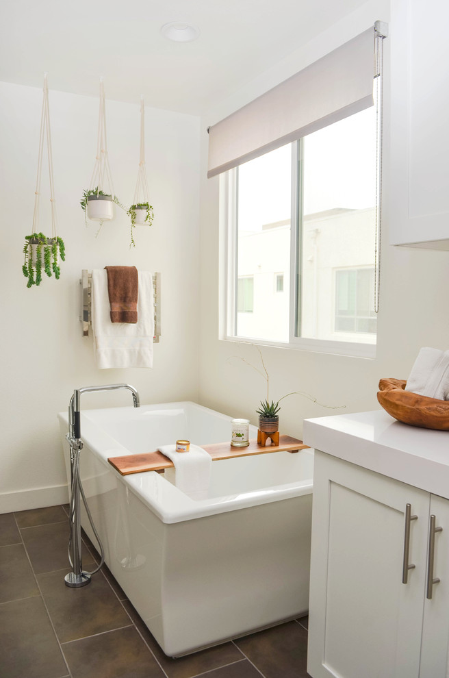 Design ideas for an expansive contemporary master bathroom in Los Angeles with shaker cabinets, white cabinets, a freestanding tub, white walls, porcelain floors, solid surface benchtops, white benchtops and brown floor.