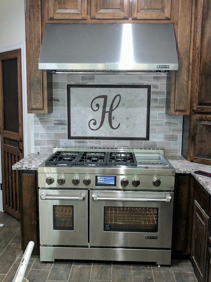 Kitchen - transitional laminate floor and brown floor kitchen idea in Austin with raised-panel cabinets, medium tone wood cabinets, granite countertops, multicolored backsplash, subway tile backsplash, stainless steel appliances and multicolored countertops