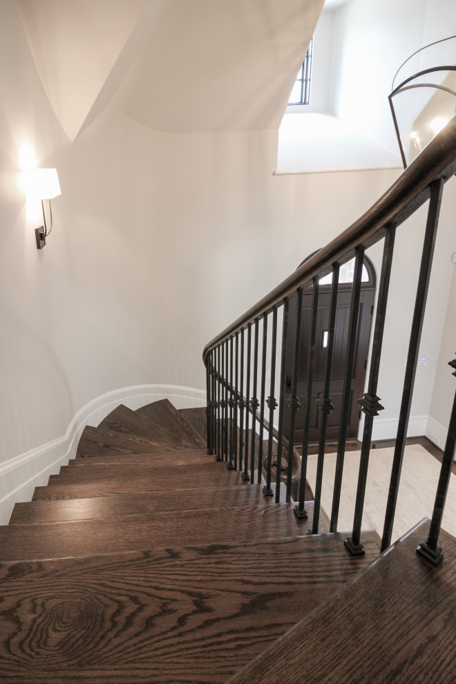 Photo of a large traditional wood floating staircase in DC Metro with painted wood risers and metal railing.