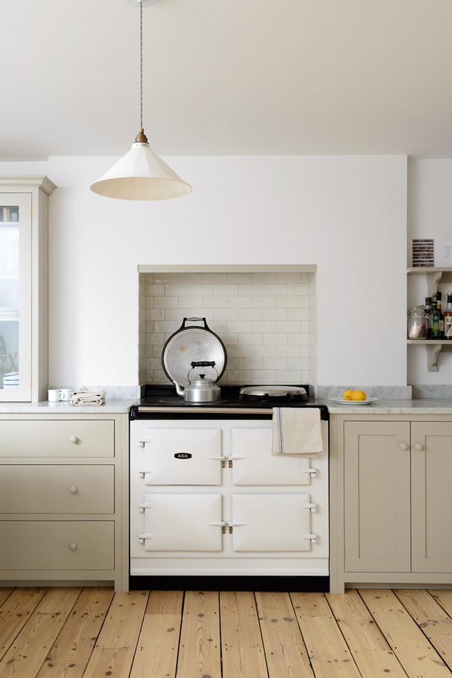 Design ideas for a mid-sized country u-shaped open plan kitchen in Sussex with a farmhouse sink, shaker cabinets, grey cabinets, marble benchtops, white splashback, subway tile splashback, white appliances, light hardwood floors and with island.