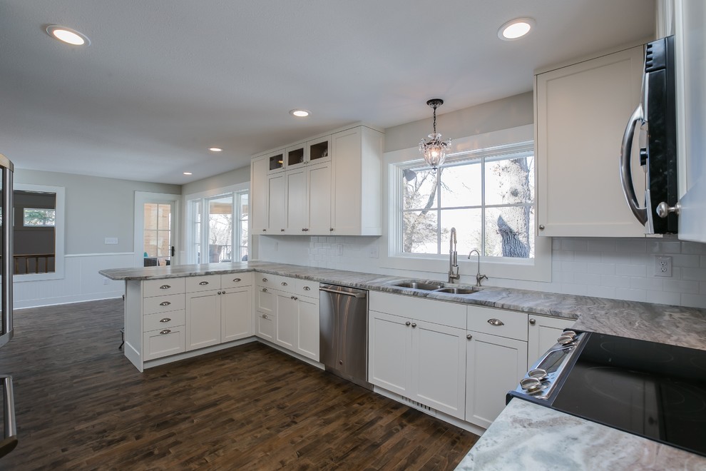 Inspiration for a large transitional u-shaped eat-in kitchen in Minneapolis with a double-bowl sink, shaker cabinets, white cabinets, quartz benchtops, white splashback, subway tile splashback, stainless steel appliances, dark hardwood floors and a peninsula.