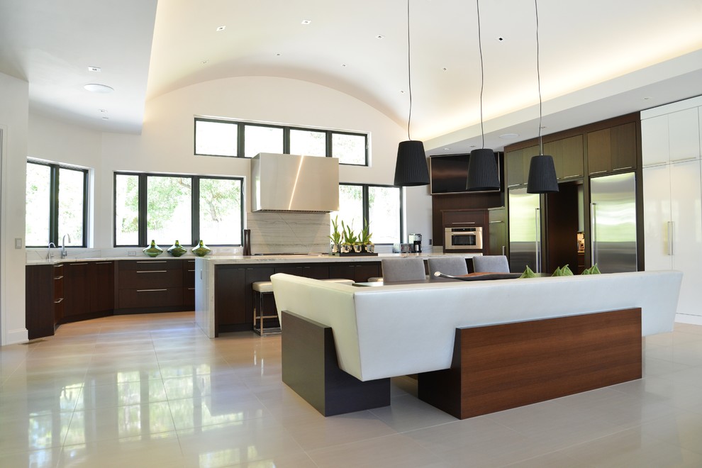This is an example of a large contemporary eat-in kitchen in St Louis with dark wood cabinets, marble benchtops, white splashback, marble splashback, stainless steel appliances, porcelain floors, with island, flat-panel cabinets and beige floor.