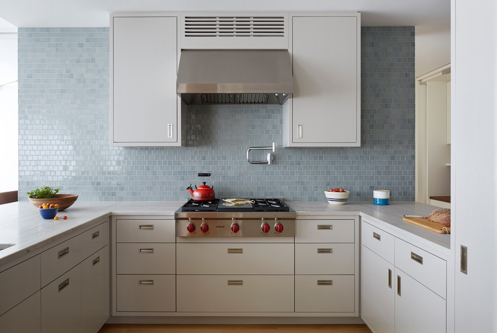 Photo of a contemporary u-shaped kitchen in New York with flat-panel cabinets, grey cabinets, blue splashback, stainless steel appliances, a peninsula and grey benchtop.