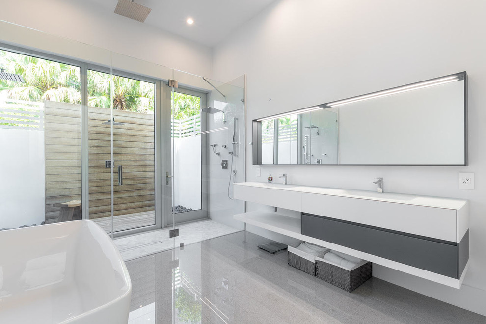 Inspiration for a large modern master bathroom in Miami with a freestanding tub, a double shower, white walls, concrete floors, an integrated sink, solid surface benchtops, grey floor, a hinged shower door and white benchtops.