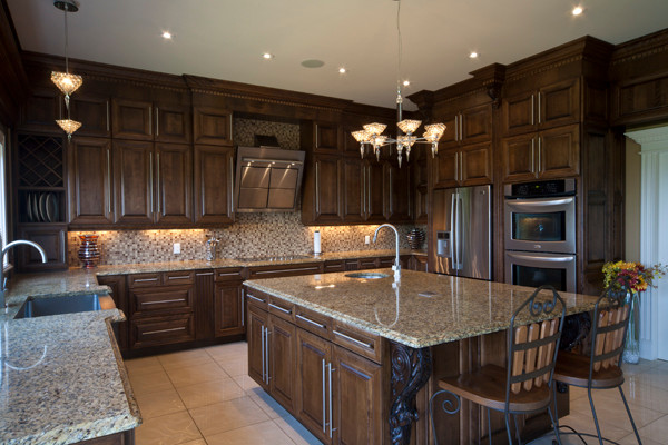 Kitchen - porcelain tile kitchen idea with a farmhouse sink, raised-panel cabinets, dark wood cabinets, granite countertops, multicolored backsplash, ceramic backsplash, stainless steel appliances and an island