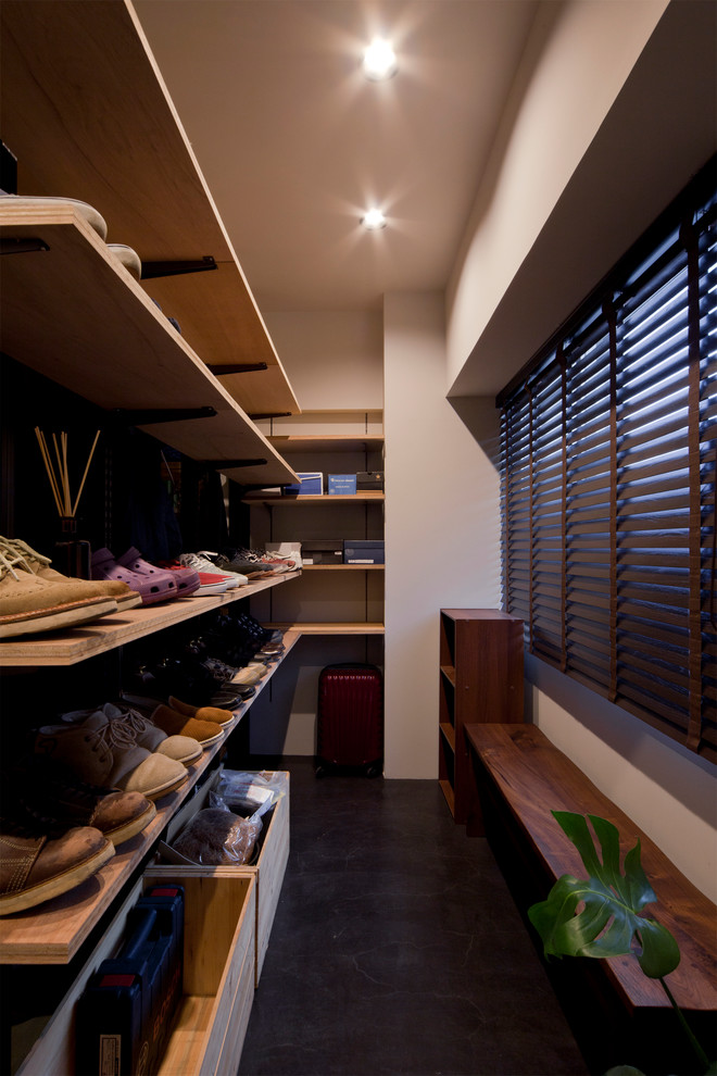 Photo of a small contemporary walk-in wardrobe in Tokyo with open cabinets, medium wood cabinets and black floor.
