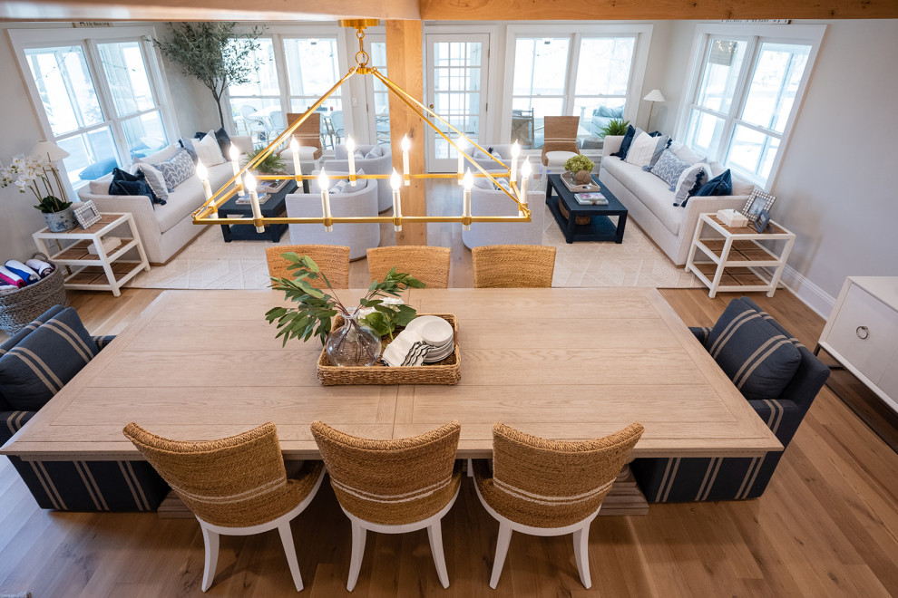 Idee per una sala da pranzo aperta verso il soggiorno stile marino con pareti beige, parquet chiaro e travi a vista